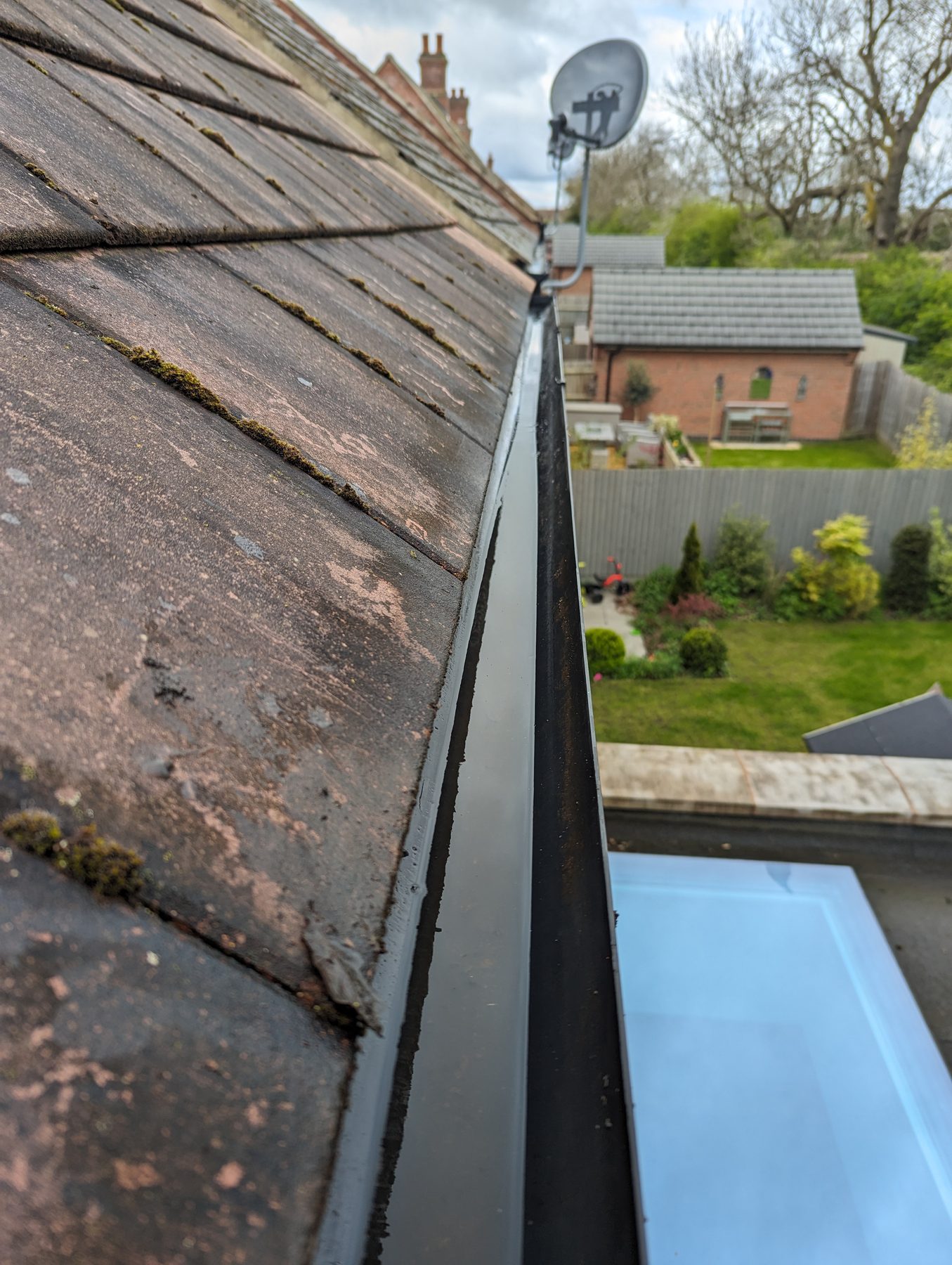 New white UPVC gutter fitted next to the old weathered concrete gutter — clear before and after